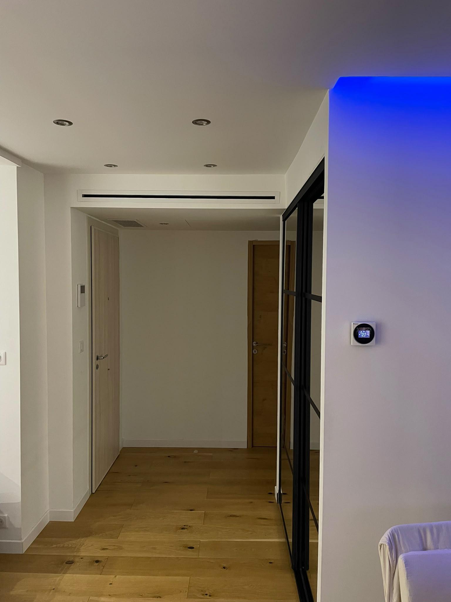 Bouche linéaire de climatisation gainable dans un séjour, avec thermostat mural